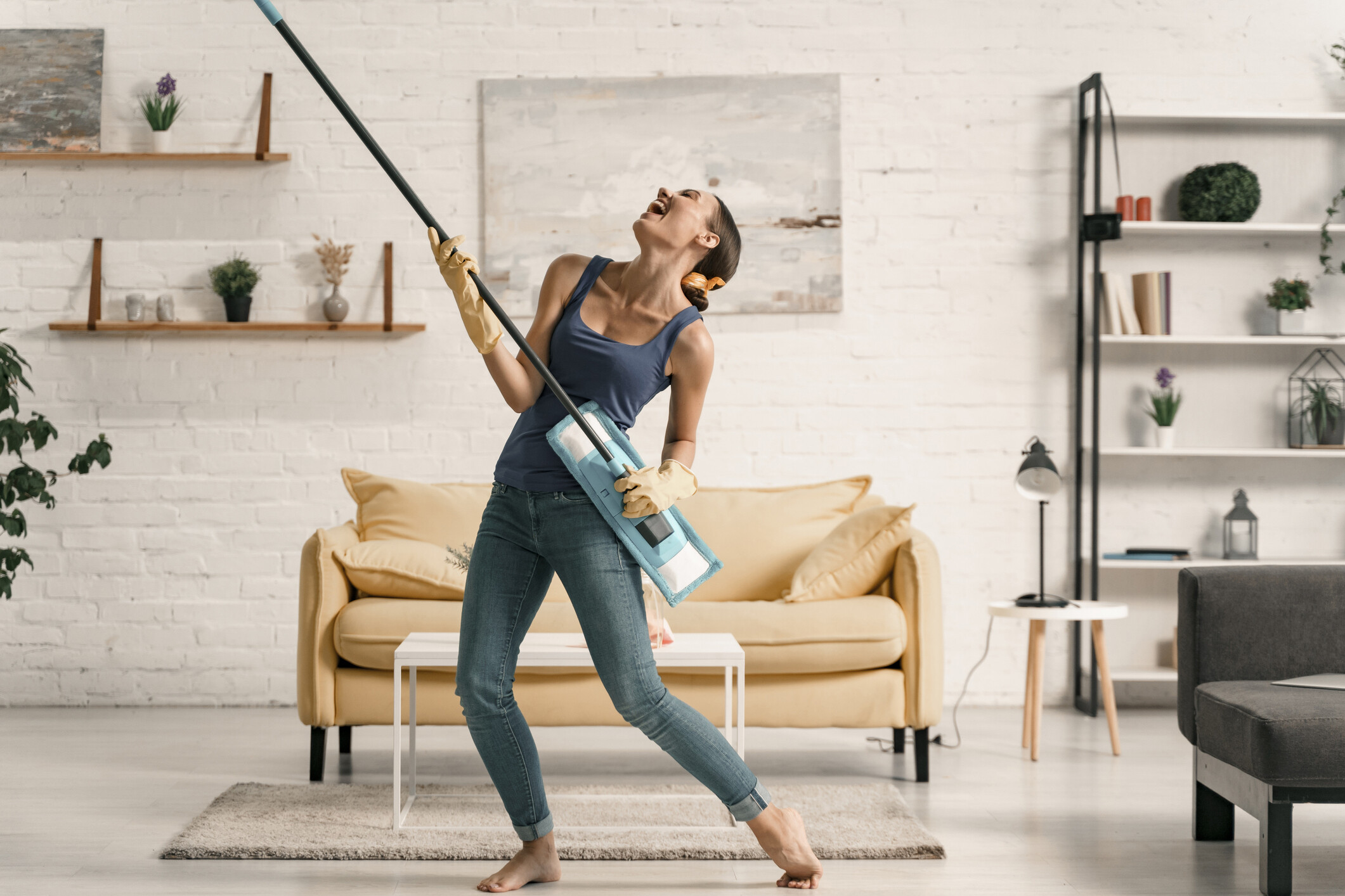 Merry woman playing with swab during cleaning Jolly young girl is dancing with mop while washing floor in living-room. Website banner